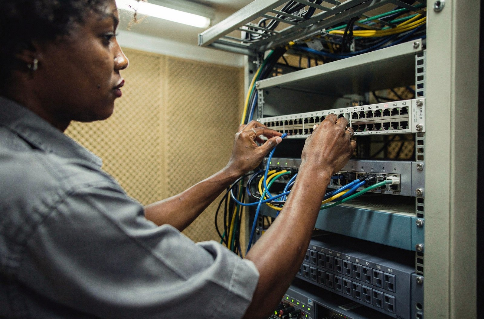 Técnica conecta um cabo de rede no painel de um rack de servidores